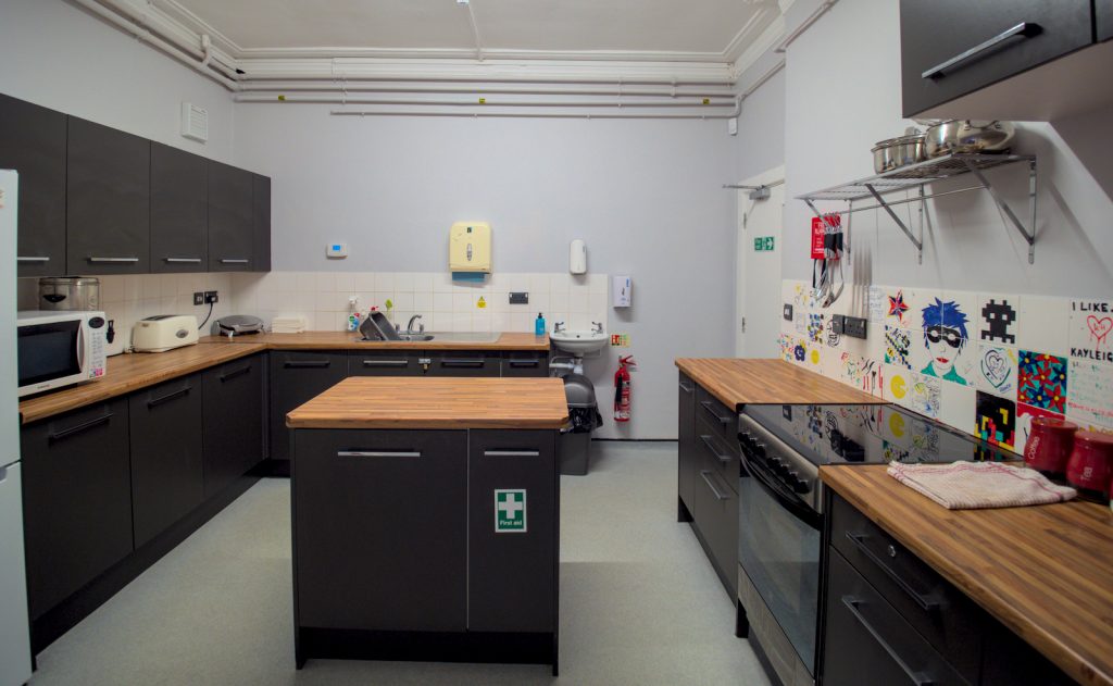 Modern kitchen with dark cabinets, wooden worktops, an island unit, and cooking and washing facilities.