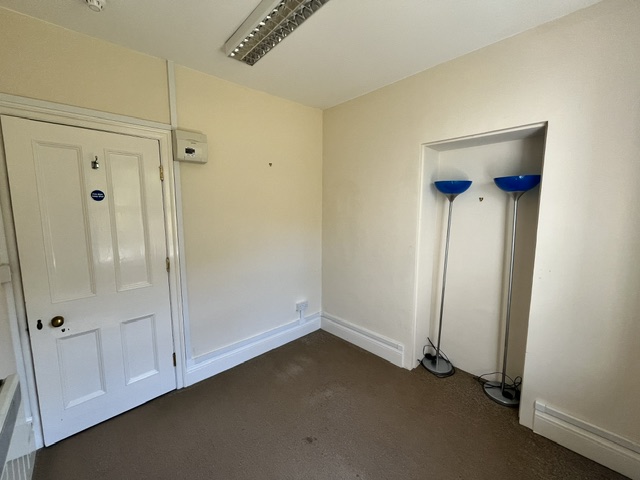 A view of the office showing the entrance door, cream-coloured walls and recessed alcove.