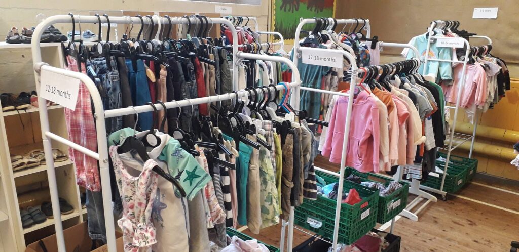 Rails of children's clothing organised by age groups at a community clothing bank.