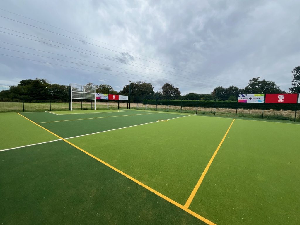 Outdoor multi-use games area with artificial turf, sports markings and goal structure.